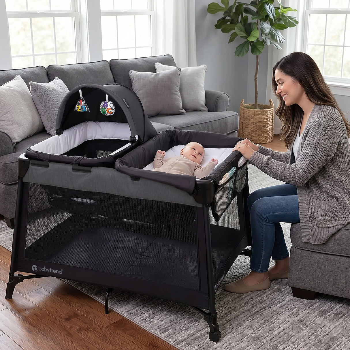 A mom is watching over her child laying in the changing table of the Baby Trend Willow Nursery Center Playard