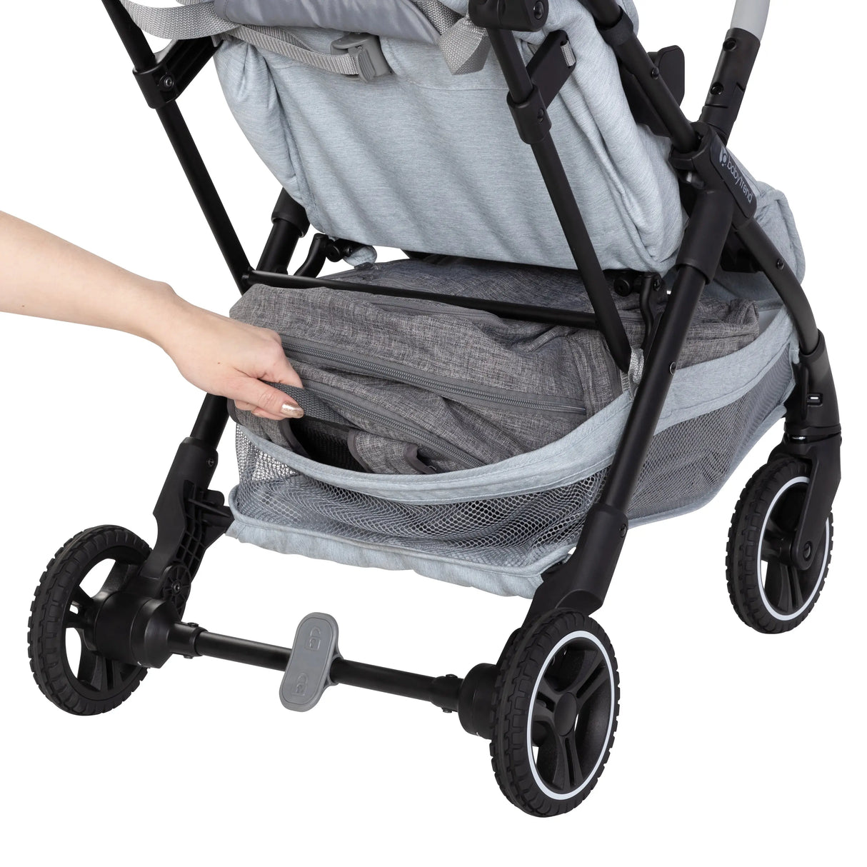 A person is pulling out a bag from the storage basket of the Baby Trend Zenda Compact All-Terrain Stroller
