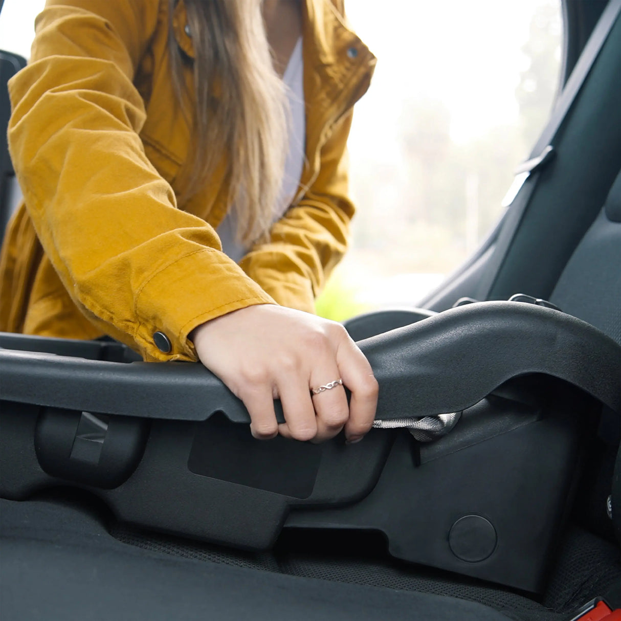 A mom is install the base from the Baby Trend EZ-Lift Infant Car Seat into a car