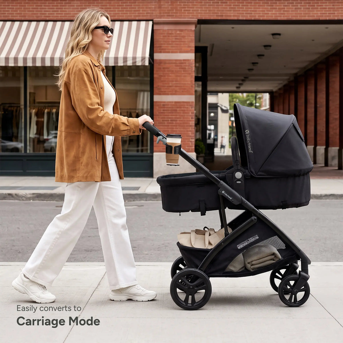 A mom is pushing her child laying in the Baby Trend Passport Switch 6-in-1 Modular Stroller while going through an outdoor shopping center