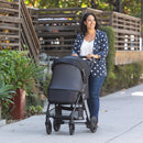 Load image into gallery viewer, A mom is strolling with her child in carriage mode and full netting cover on the Baby Trend Passport Carriage DLX Stroller Travel System