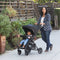 A mother is strolling with her child outside with the Baby Trend Passport Carriage DLX Stroller Travel System