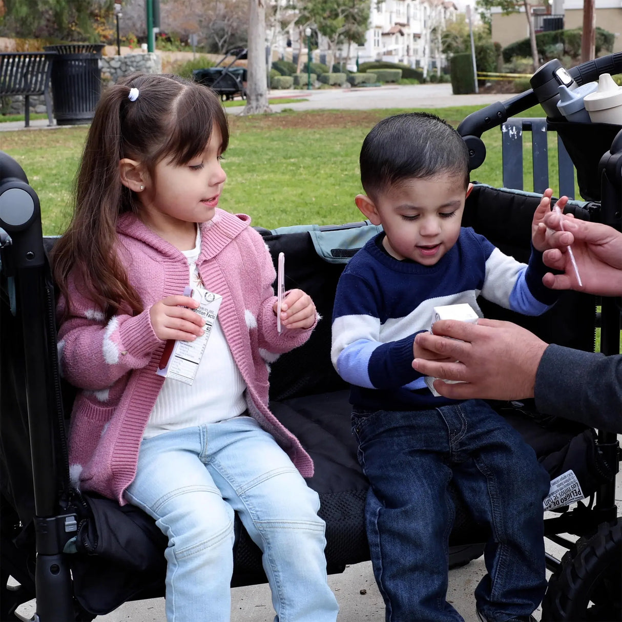 Two children sitting in the Quest PLUS 3-in-1 Stroller Wagon as a bench