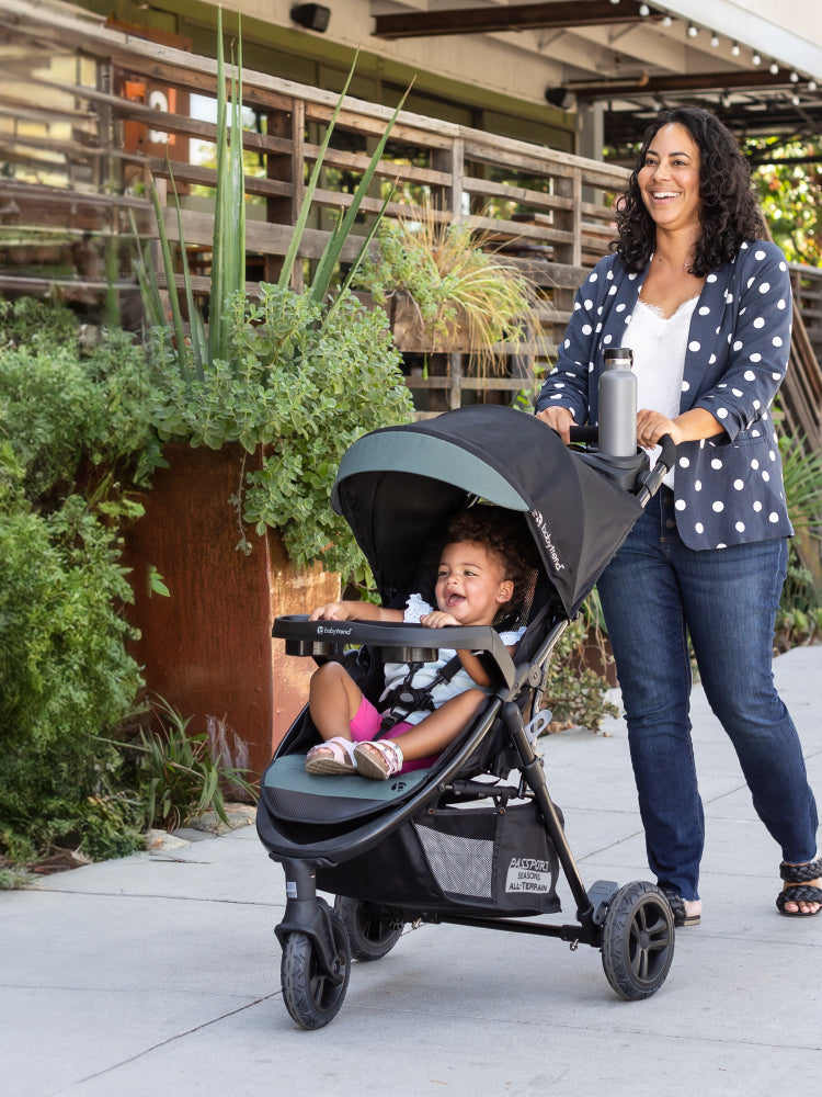 A mom is pushing her child in the Baby Trend Passport Seasons All-Terrain Stroller
