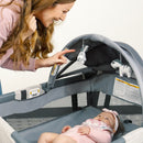 Load image into gallery viewer, Baby laying in the Baby Trend Deluxe II Nursery Center Playard with mom watching her child