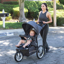 Load image into gallery viewer, Mom is pushing the Baby Trend Expedition Jogger Travel System with her child sitting