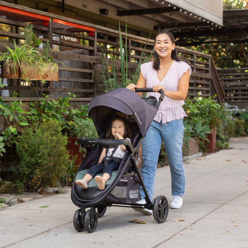 Mom is pushing her child in the Baby Trend Sonar Cargo 3-Wheel Stroller Travel System