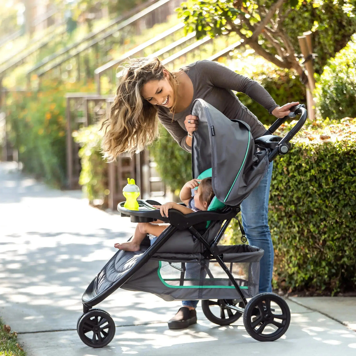 Mom looking over her child outdoor in the Baby Trend EZ Ride Stroller Travel System with EZ-Lift 35 Infant Car Seat