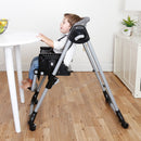 Load image into gallery viewer, A child sitting at the dining table with the booster mode on the Baby Trend A La Mode Snap Gear 5-in-1 High Chair