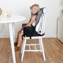 Load image into gallery viewer, A child sitting at the dining table in booster mode from the Baby Trend A La Mode Snap Gear 5-in-1 High Chair