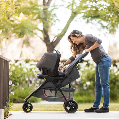 Parent leaning over the EZ-Lift Infant Car Seat attached to the Baby Trend EZ Ride stroller, set up as a travel system