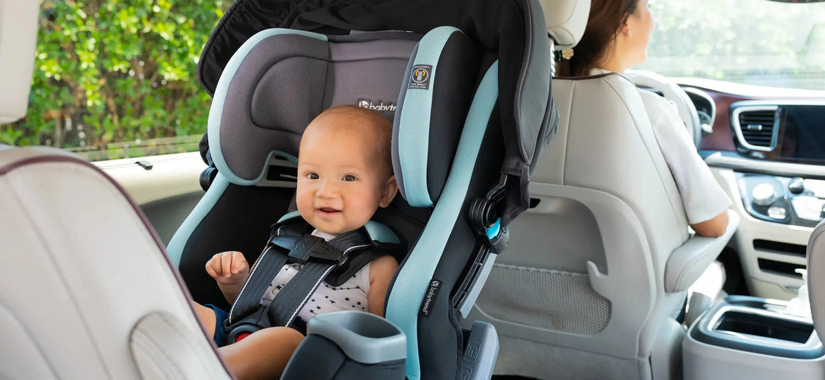 Smiling baby buckled into a Baby Trend Cover Me 4-in-1 Convertible Car Seat in the back seat of a car