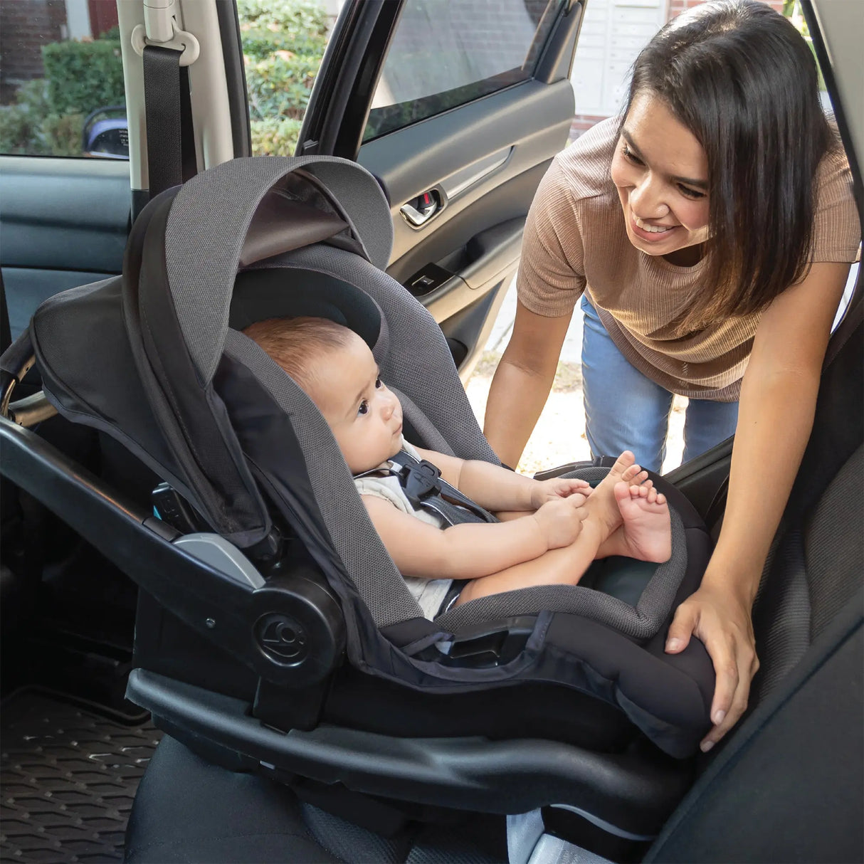 Woman adjusting a baby in a Baby Trend Secure-Lift Infant Car Seat inside a vehicle