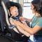 A mom is placing her child in the Baby Trend Trooper SLIM 3-in-1 Convertible Car Seat 