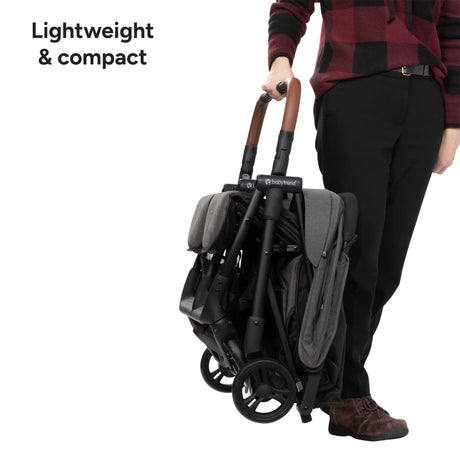 Person holding a compact and lightweight Baby Trend York Compact Side-By-Side Double Stroller