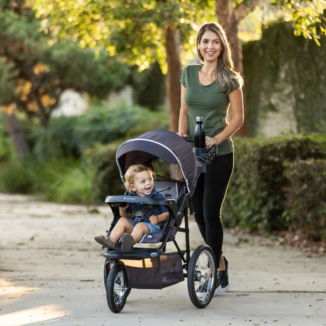 A mom is pushing her child in the Baby Trend XCEL-R8 PLUS Jogger Stroller with LED