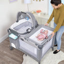 Load image into gallery viewer, A mother looking after her child laying in the Lullaby Nursery Suite EZ-Fold Playard with Portable Rocking Lounger