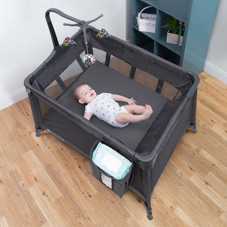 A child laying in the Baby Trend Sol Nursery Center Playard