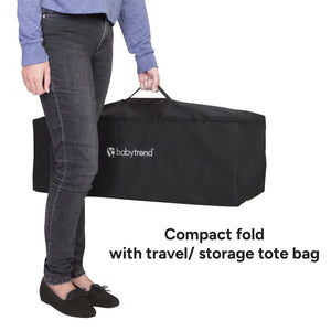 A mother holding the Baby Trend Willow Nursery Center Playard while compacted fold with travel storage tote bag