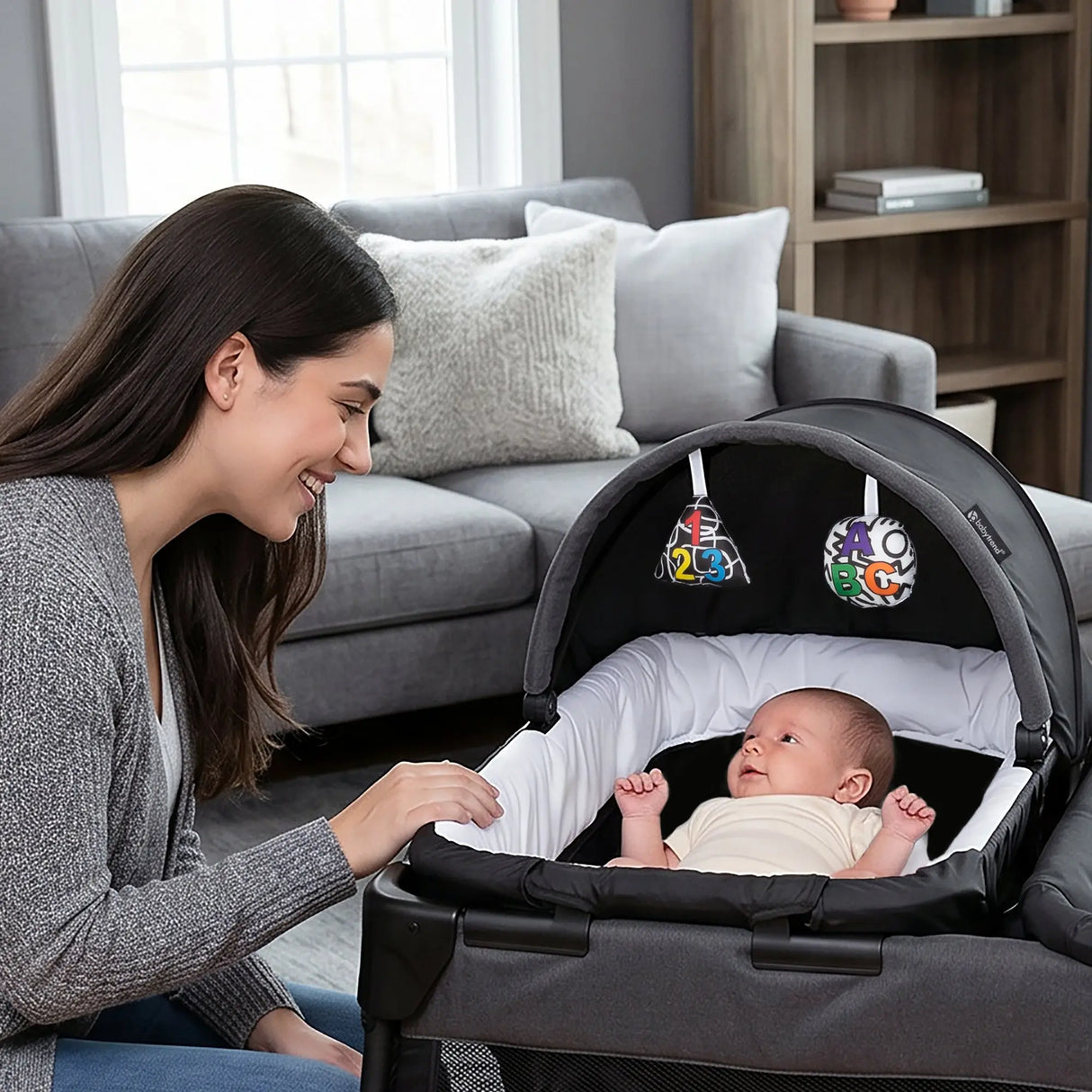 A mom is watching her child laying in the napper of the Baby Trend Willow Nursery Center Playard within their home