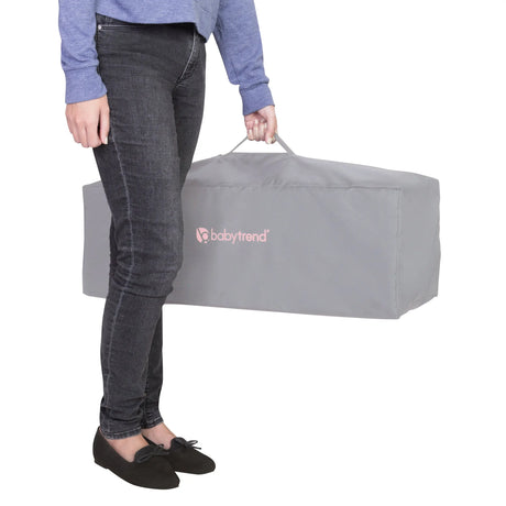 A mother is holding the folded Baby Trend EZ Rest Playard