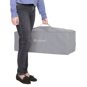 A mom is carrying the Baby Trend EZ Rest Playard folded in the travel bag