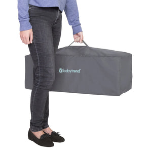 A mother is carrying the Baby Trend EZ Rest Deluxe Nursery Center in the travel bag