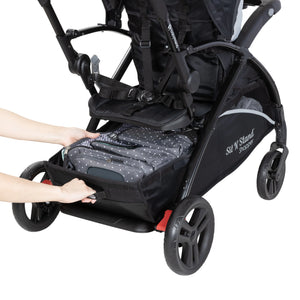 A person is accessing the rear basket of the Baby Trend Sit N Stand 5-in-1 Shopper Stroller