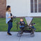 Mom strolling outdoor with the Baby Trend Sit N' Stand Ultra Stroller and her two children