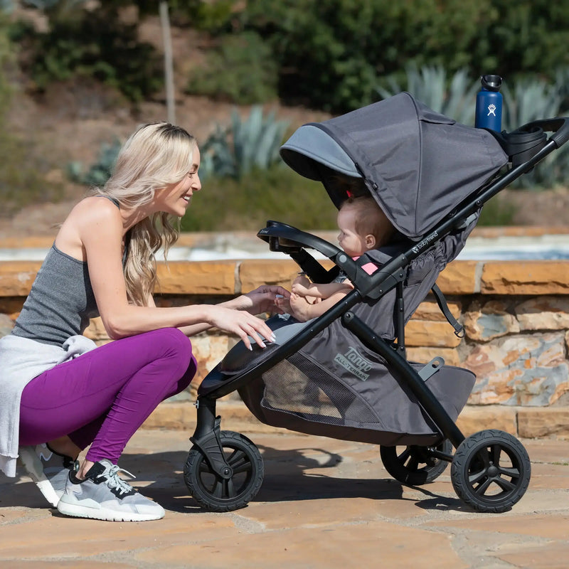 A mom is looking after her child sitting in the Baby Trend Tango 3 All-Terrain Stroller