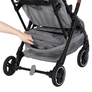 A person is accessing the storage basket of the Baby Trend Zenda Compact All-Terrain Stroller at the rear