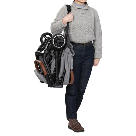 A person is carrying the Baby Trend Zenda Compact All-Terrain Stroller using the shoulder strap