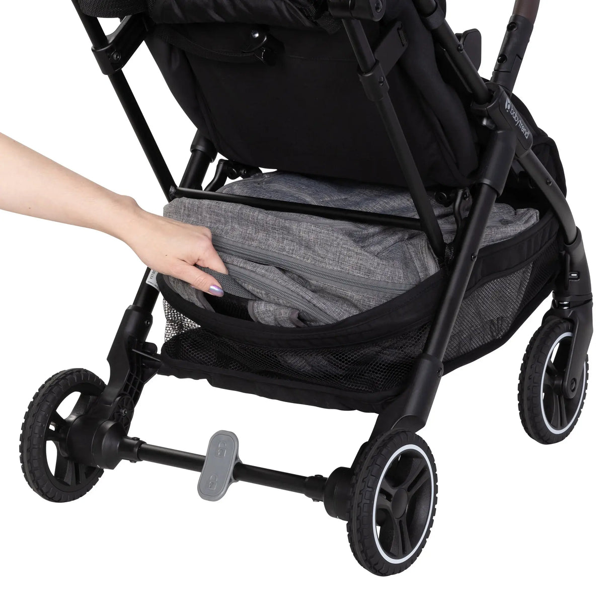 A person is pulling out a bag from the storage basket of the Baby Trend Zenda Compact All-Terrain Stroller 