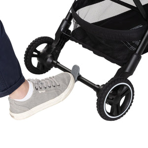 A person is pushing on the brake of the Baby Trend Zenda Compact All-Terrain Stroller 