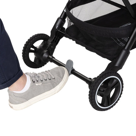A person is pushing on the brake of the Baby Trend Zenda Compact All-Terrain Stroller 