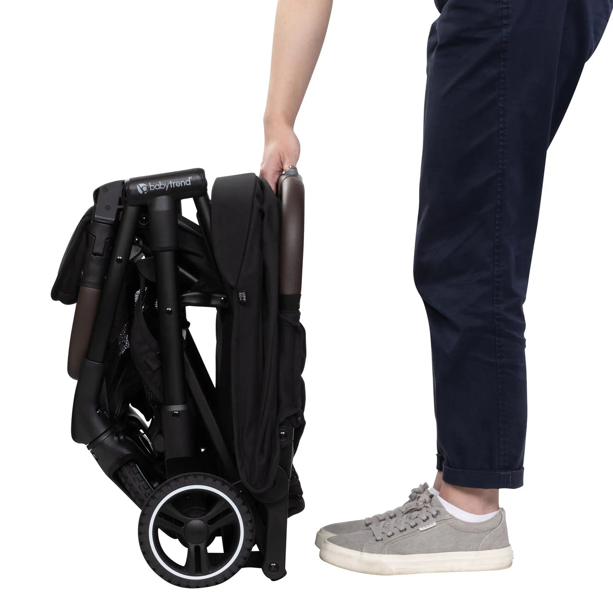 Side view of a person just finishing folding the Baby Trend Zenda Compact All-Terrain Stroller 