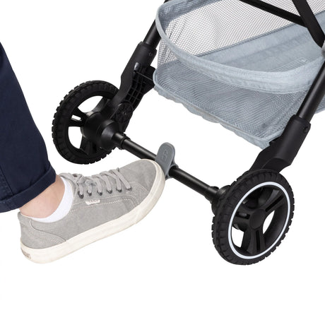 A person is using their foot to press down on the brake of the Baby Trend Zenda Compact All-Terrain Stroller