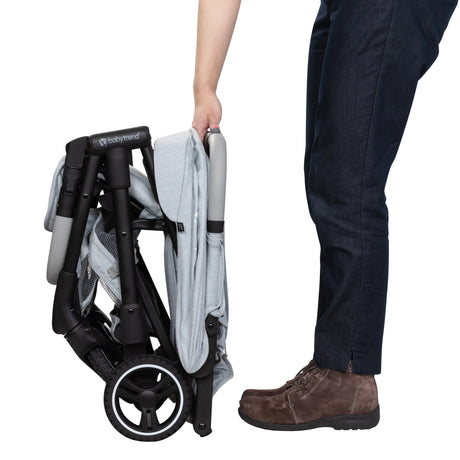 A person just finished folding the Baby Trend Zenda Compact All-Terrain Stroller
