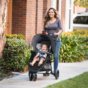 A mother is taking her child on stroll through the apartment complex with the Baby Trend EZ Ride Stroller