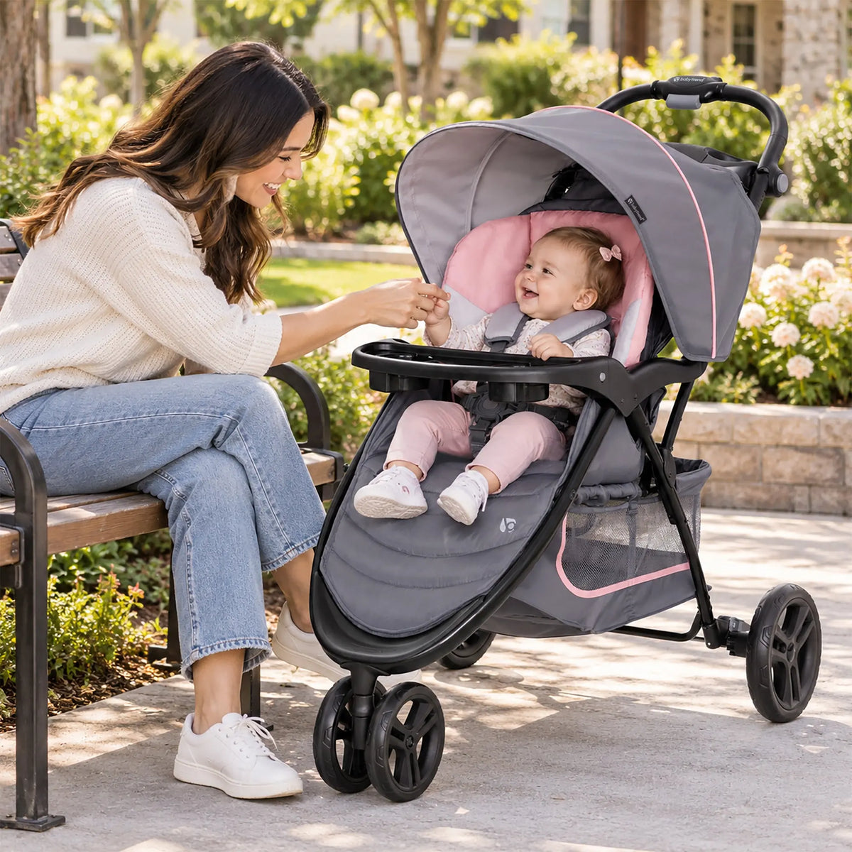 A mom sitting on a bench with her child next to her in a Baby Trend EZ Ride Stroller at the park