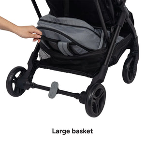 A hand is pulling out a backpack under the Baby Trend Sonar Compact Lightweight Stroller basket