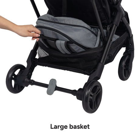 A hand is pulling out a backpack under the Baby Trend Sonar Compact Lightweight Stroller basket