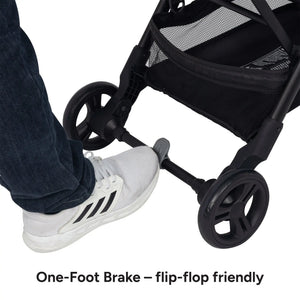 A foot is on the brake of the Baby Trend Sonar Compact Lightweight Stroller
