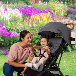 A mom is watching her child sitting in the Baby Trend Sonar Compact Lightweight Stroller
