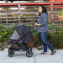 Load image into gallery viewer, Mom is strolling her child outdoor in the carriage mode with the Baby Trend Passport Carriage DLX Stroller Travel System