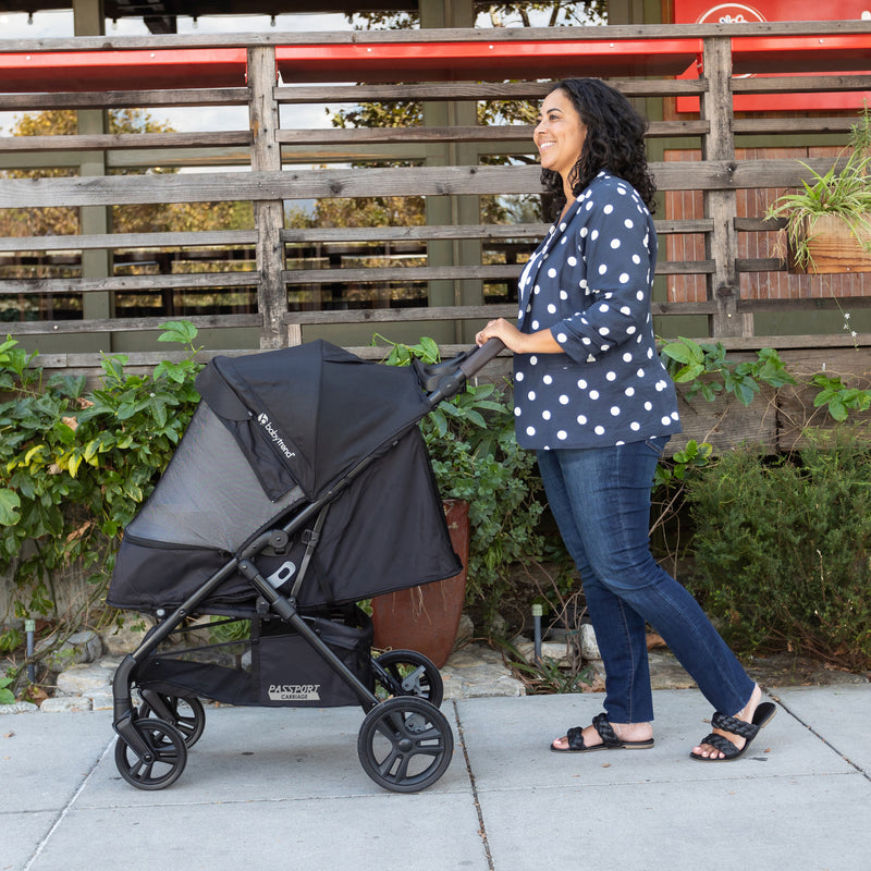 Mom is strolling her child outdoor in the carriage mode with the Baby Trend Passport Carriage DLX Stroller Travel System