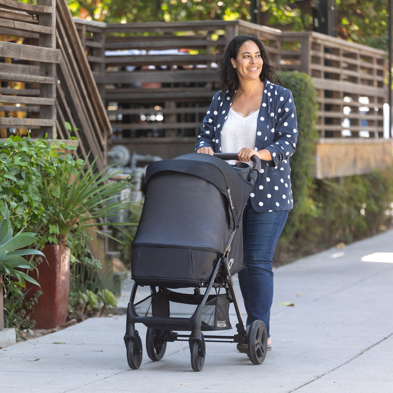 A mom is strolling with her child in carriage mode and full netting cover on the Baby Trend Passport Carriage DLX Stroller Travel System