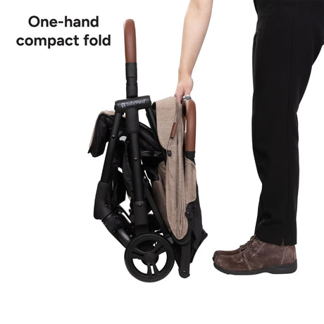 A person folding the Baby Trend York Compact Stroller into a compact fold