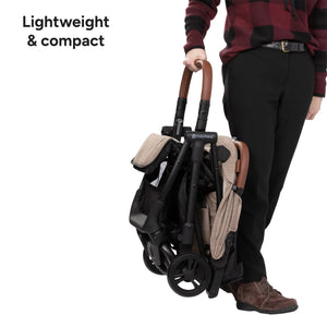 A person is holding up the Baby Trend York Compact Stroller as it is lightweight and compact
