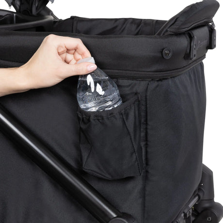 A hand is taking out a water bottle from the side pocket of the Baby Trend Expedition 2-in-1 Stroller Wagon